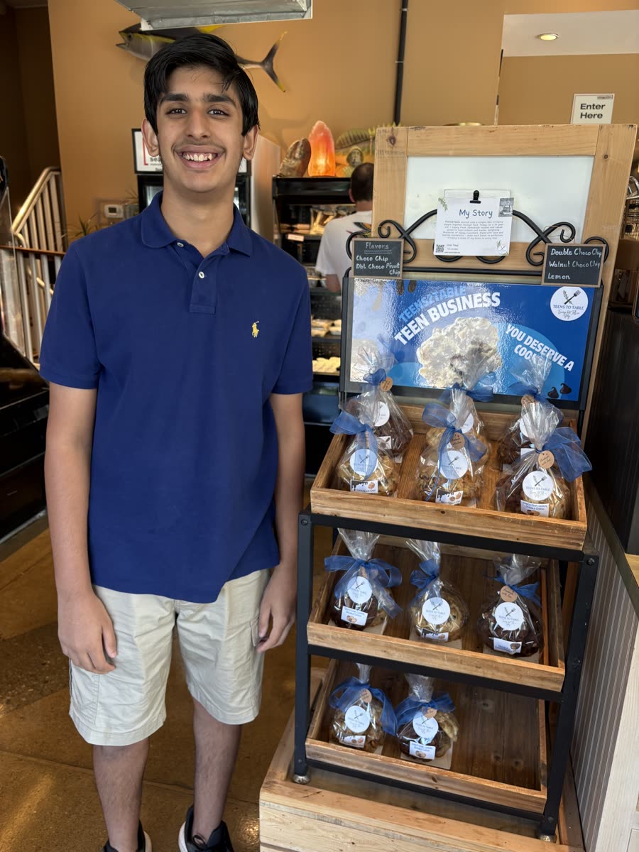 The Teens2Table founder standing beside the cookie display stand at a local shop